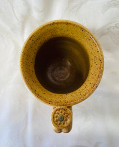 A Mug:  (Goldenrod on Speckled Clay with a Daisy Thumb Rest)