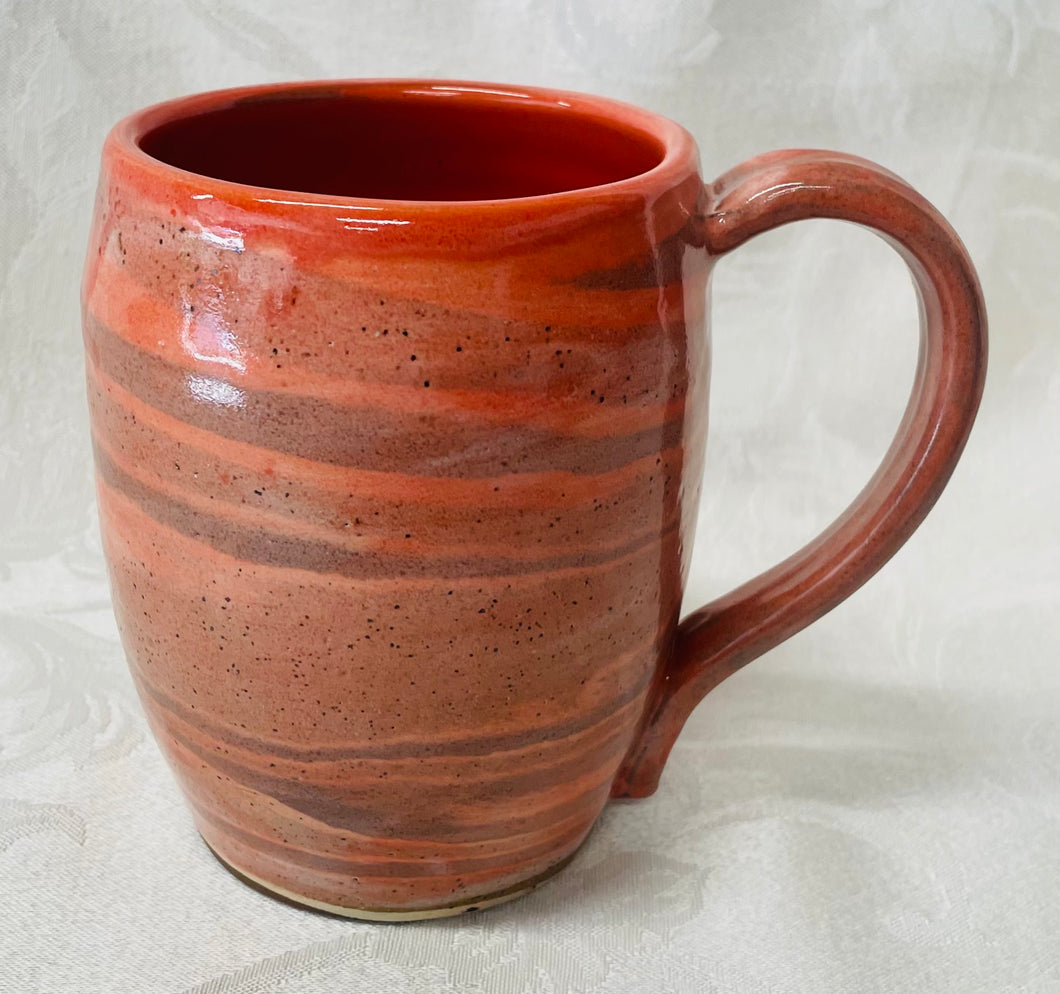 A Mug:  (Peach Colored Ceramic Mug on Tri-Colored Clay with a Turtle Stamp on the Handle Bottom))