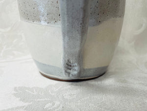 A Mug:  (White Ceramic Mug on Tri-Colored Clay with a Leaf Stamp on the Handle Bottom)